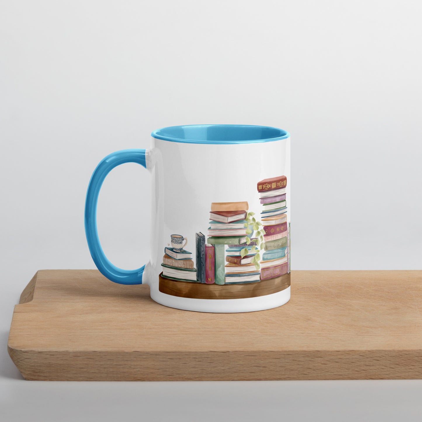 A coffee mug for book lovers featuring a watercolor bookshelf design all around on white ceramic. The interior is a bright blue ceramic.