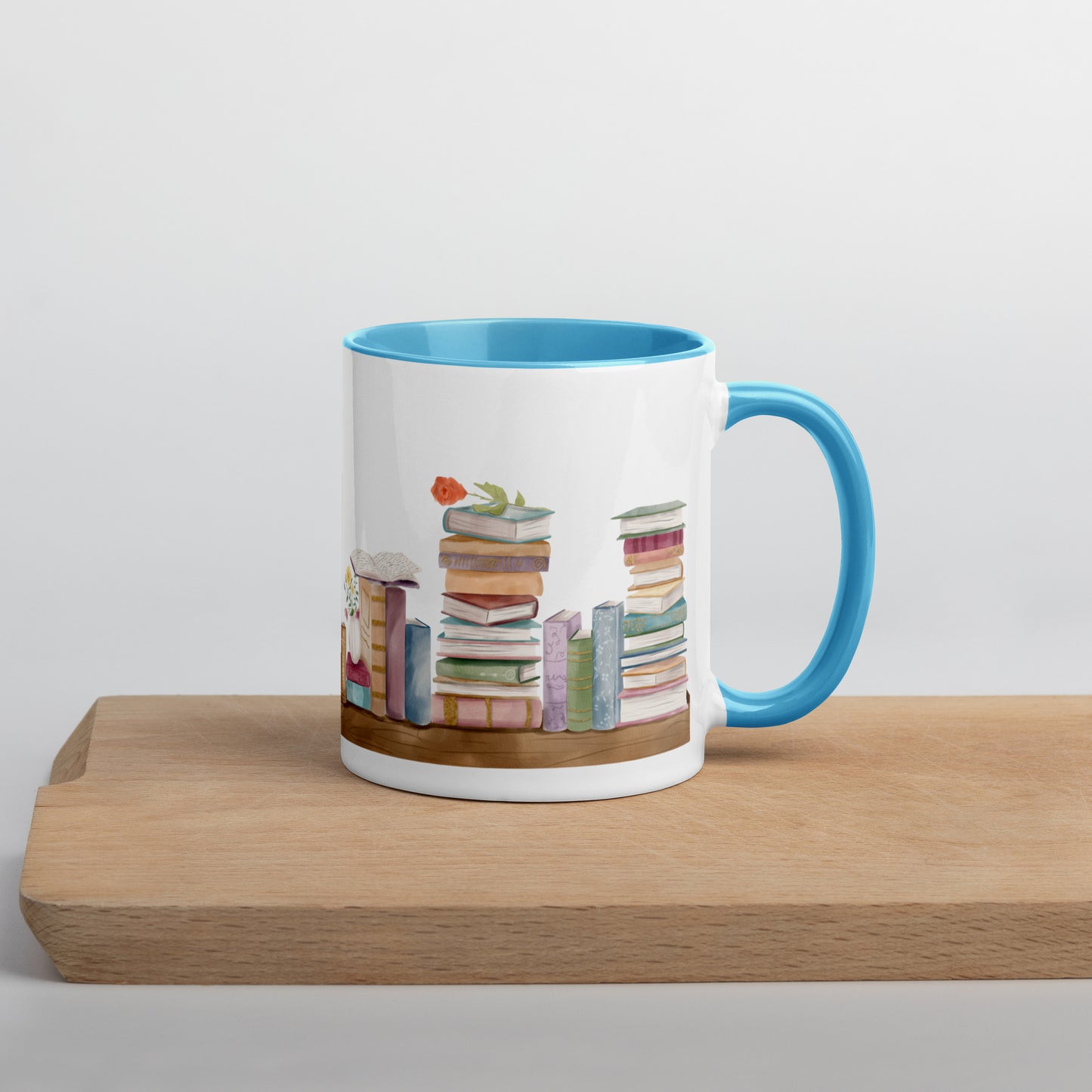 A coffee mug for book lovers featuring a watercolor bookshelf design all around on white ceramic. The interior is a bright blue ceramic.