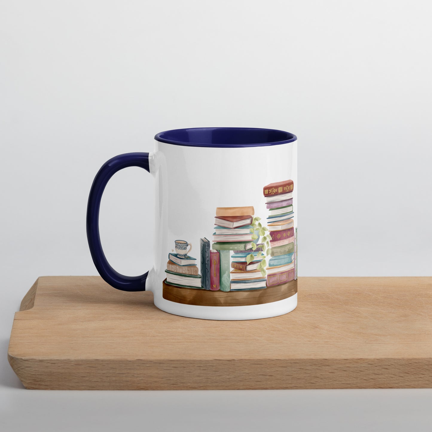 A coffee mug for book lovers featuring a watercolor bookshelf design all around on white ceramic. The interior is a dark blue ceramic.