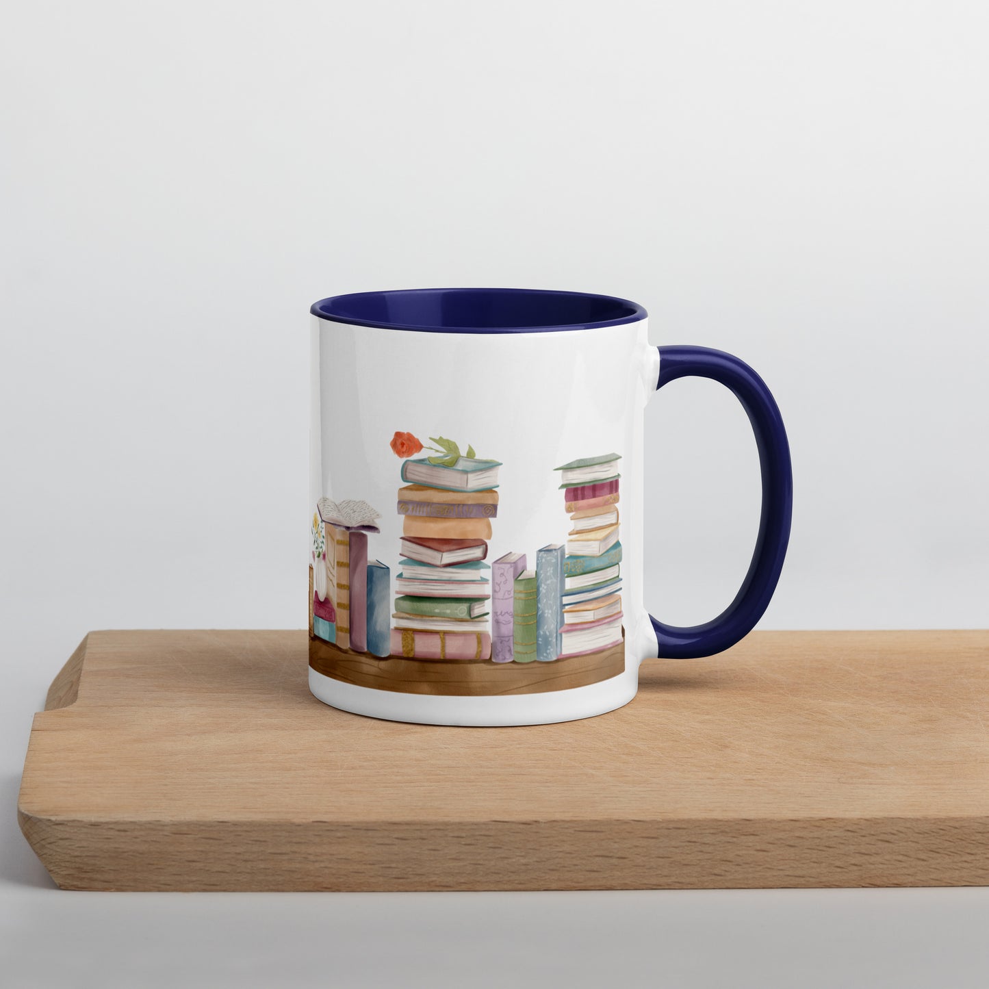 A coffee mug for book lovers featuring a watercolor bookshelf design all around on white ceramic. The interior is a dark blue ceramic.