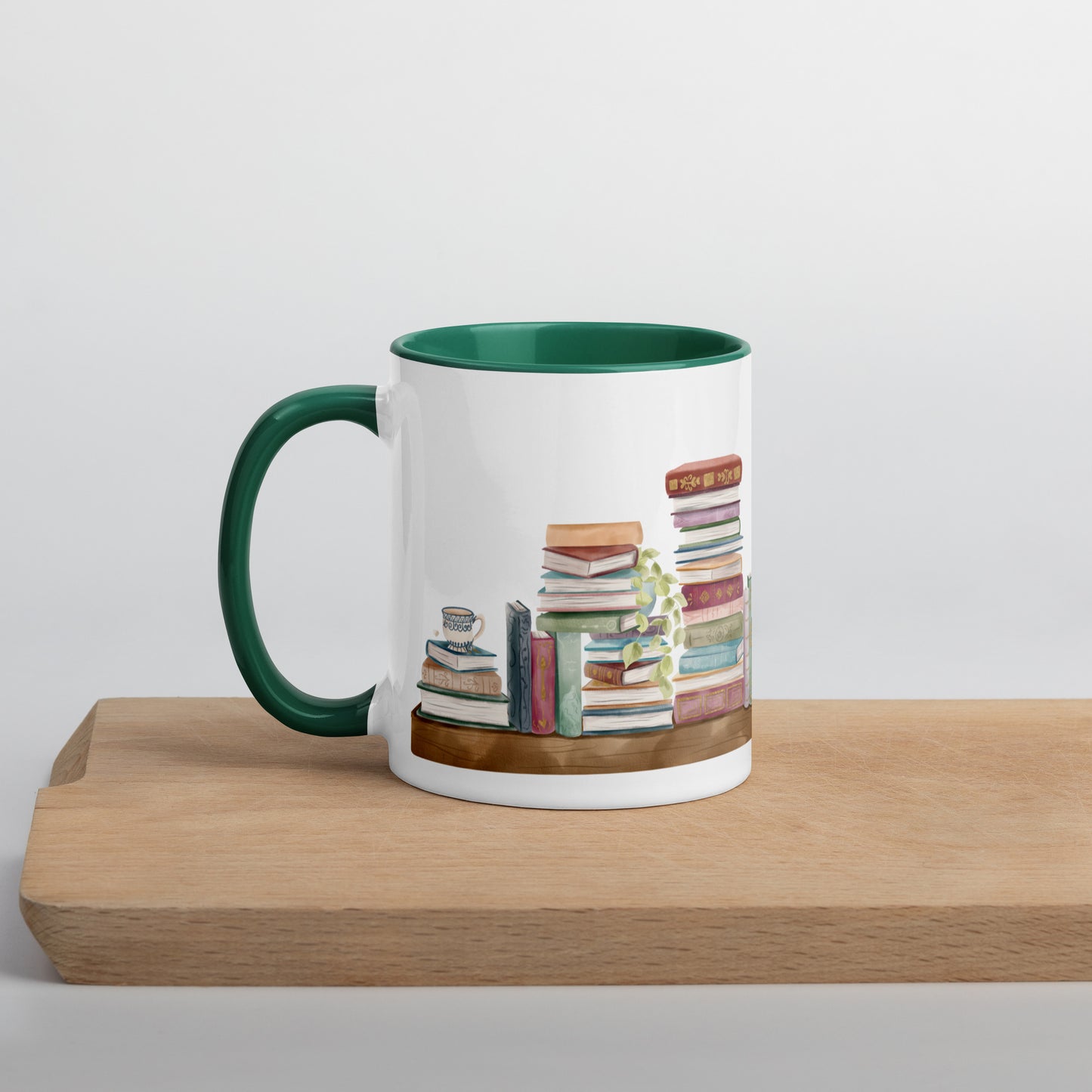 A coffee mug for book lovers featuring a watercolor bookshelf design all around on white ceramic. The interior is a dark green ceramic.