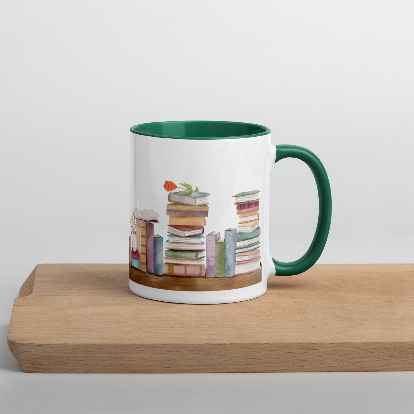 A coffee mug for book lovers featuring a watercolor bookshelf design all around on white ceramic. The interior is a dark green ceramic.