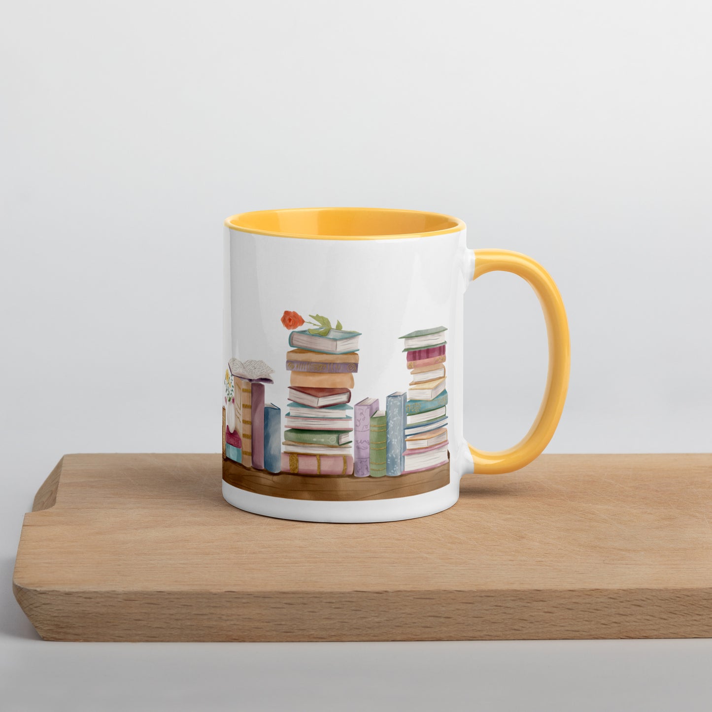 A coffee mug for book lovers featuring a watercolor bookshelf design all around on white ceramic. The interior is a golden yellow ceramic.