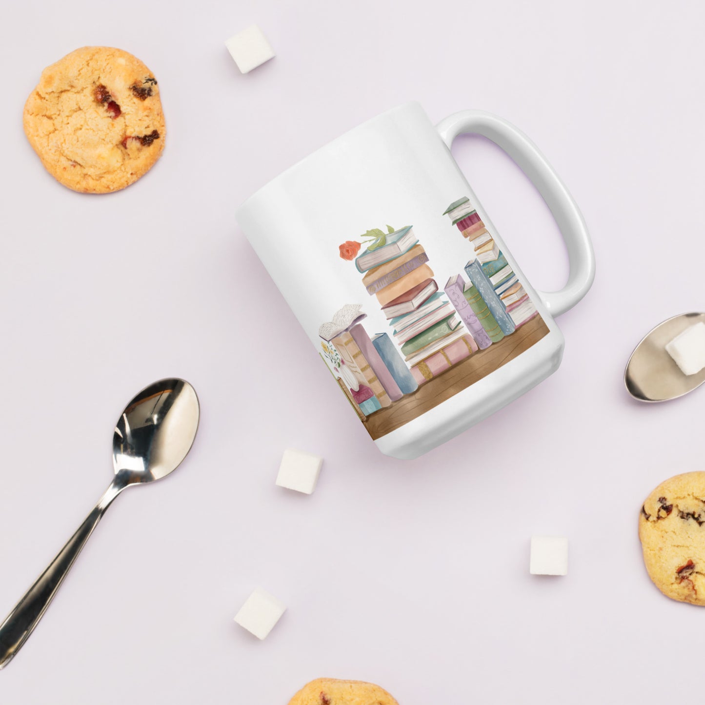 A white ceramic mug for book lovers featuring a wrap around design with stacks of watercolor illustrated books along a shelf.
