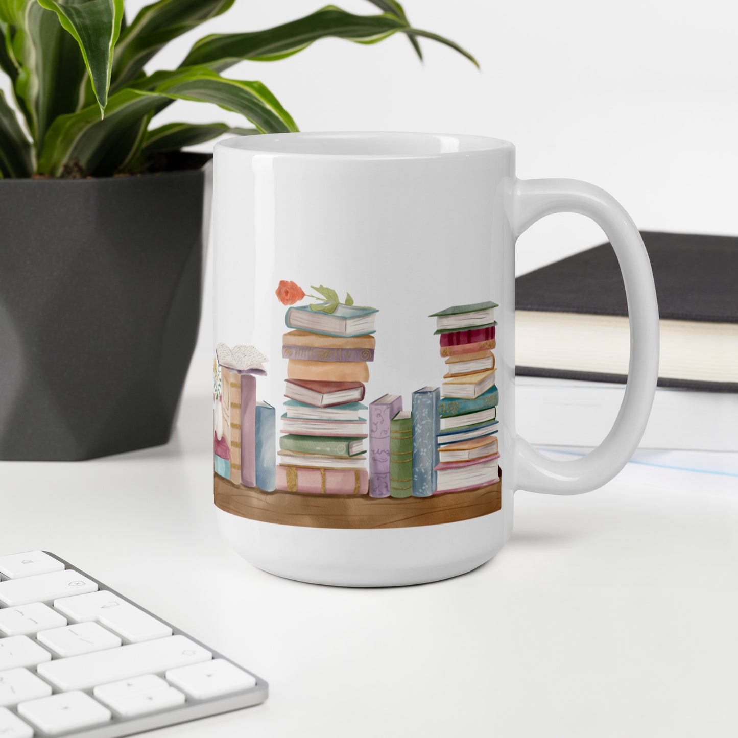 A white ceramic mug for book lovers featuring a wrap around design with stacks of watercolor illustrated books along a shelf.