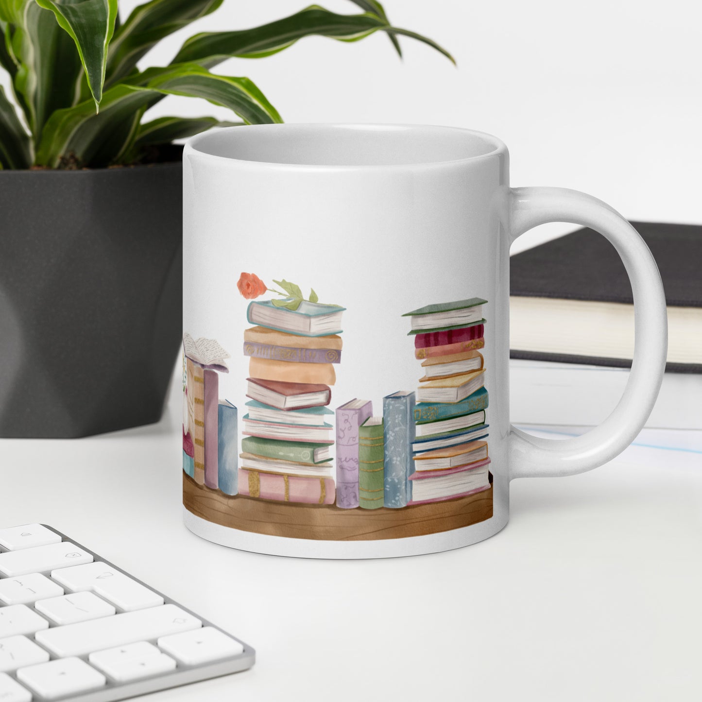 A white ceramic mug for book lovers featuring a wrap around design with stacks of watercolor illustrated books along a shelf.